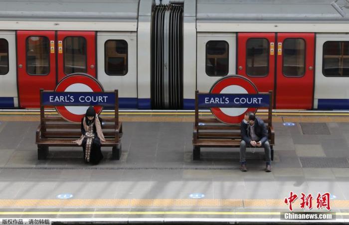 资料图：英国“有条件解封”，出行的伦敦市民坐在伯爵法院站的长凳上。